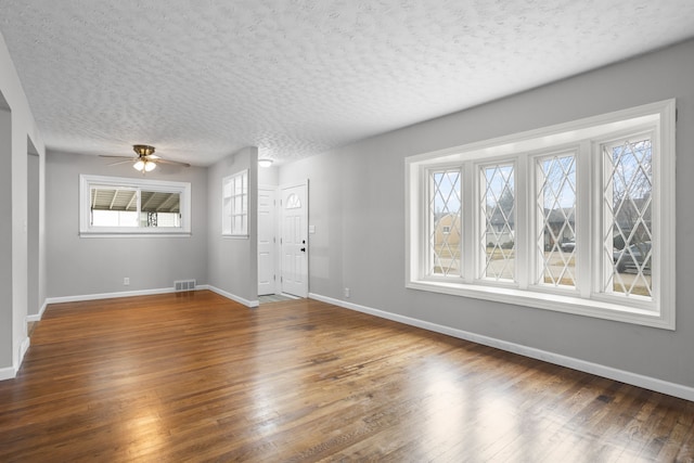 unfurnished room featuring ceiling fan, dark wood-type flooring, and a textured ceiling