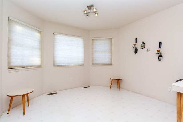 interior space featuring light floors, a wealth of natural light, visible vents, and baseboards