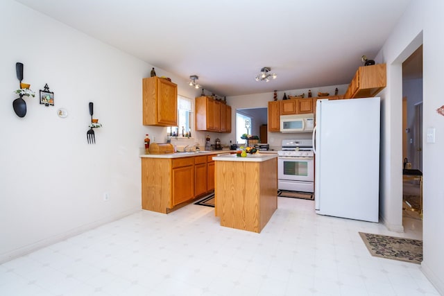 kitchen featuring light floors, white appliances, light countertops, a kitchen island, and baseboards