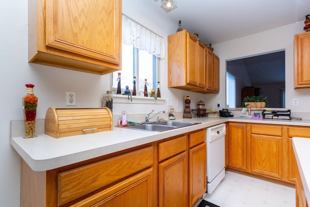kitchen featuring brown cabinets, a sink, light countertops, dishwasher, and light floors
