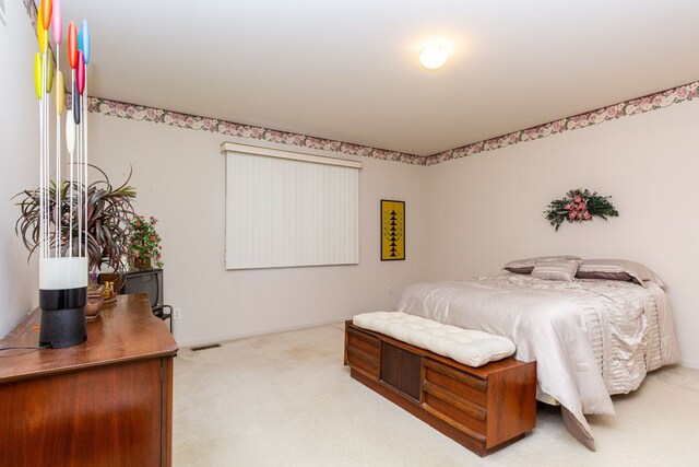 bedroom featuring baseboards, visible vents, and light colored carpet