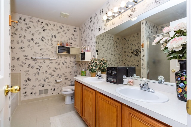 bathroom featuring a stall shower, visible vents, wallpapered walls, and a sink