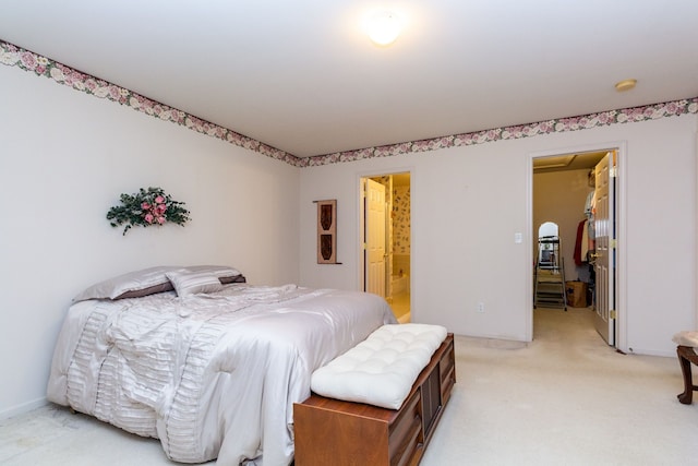 bedroom with a walk in closet, light carpet, connected bathroom, and a closet