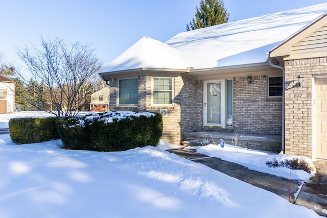 view of snowy exterior with brick siding