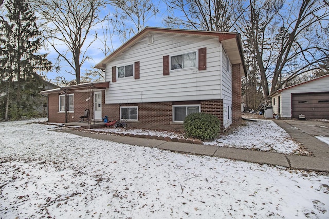 snow covered property featuring a garage and an outdoor structure