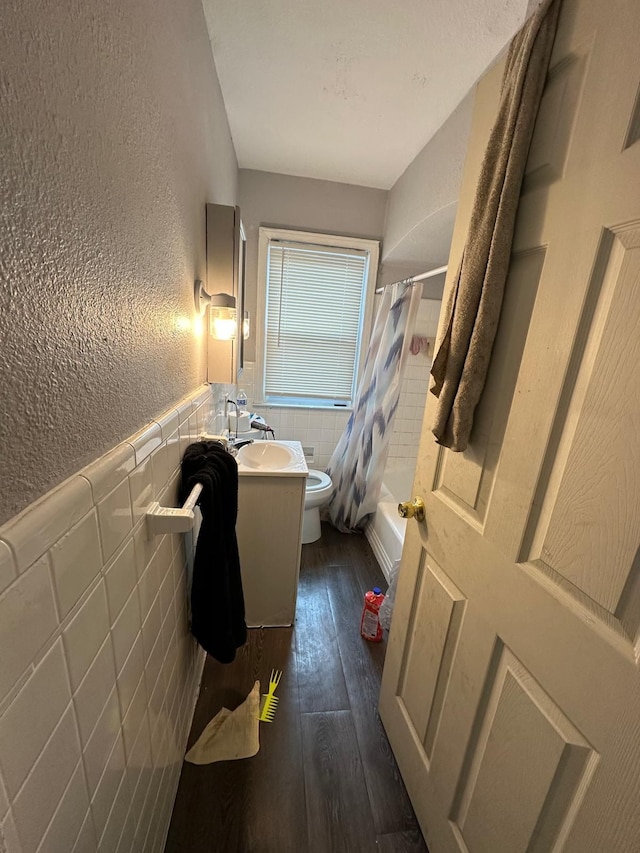 full bathroom with toilet, tile walls, vanity, shower / bath combo, and hardwood / wood-style flooring