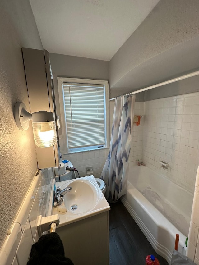 bathroom with vanity, hardwood / wood-style floors, shower / bath combination with curtain, and tile walls