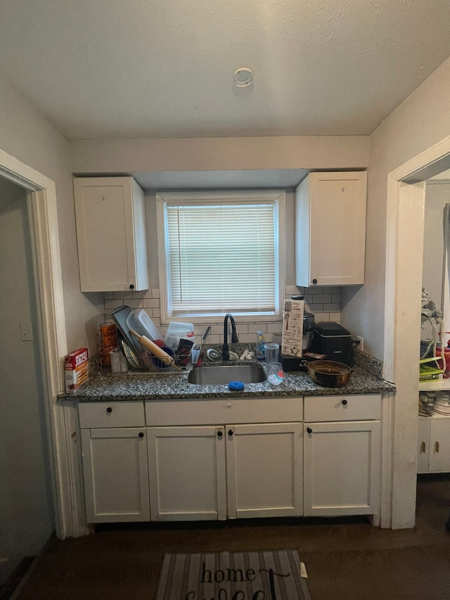 19307 Mansfield St, Detroit, MI 48235 - kitchen with dark stone counters, white cabinets, a sink, and decorative backsplash
