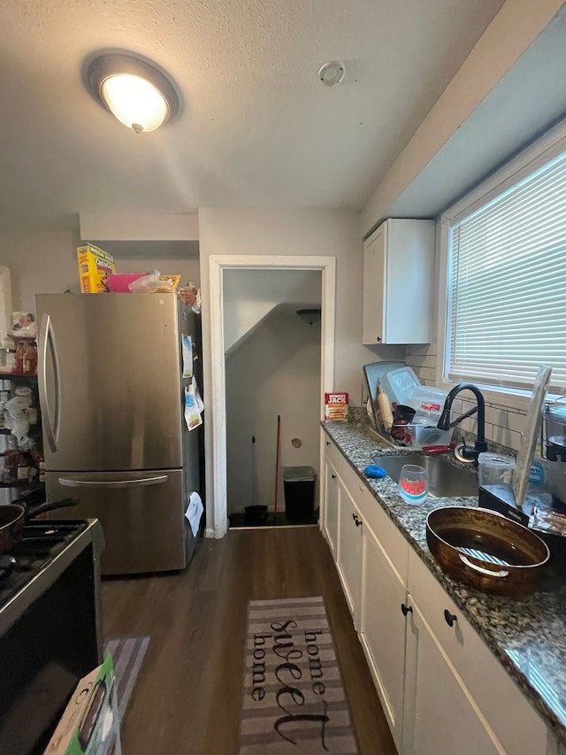 19307 Mansfield St, Detroit, MI 48235 - kitchen featuring white cabinetry, decorative backsplash, dark wood finished floors, a sink, and freestanding refrigerator
