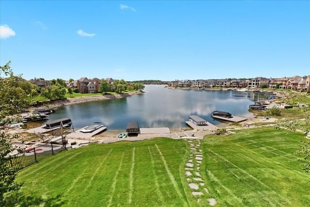 view of dock with a water view and a lawn