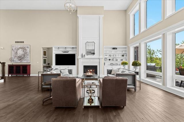 living room featuring an inviting chandelier, a towering ceiling, and dark wood-type flooring