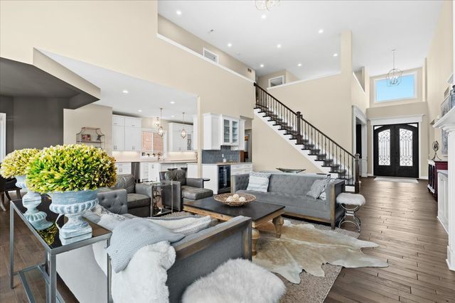 living room with beverage cooler, a high ceiling, a notable chandelier, dark wood-type flooring, and french doors