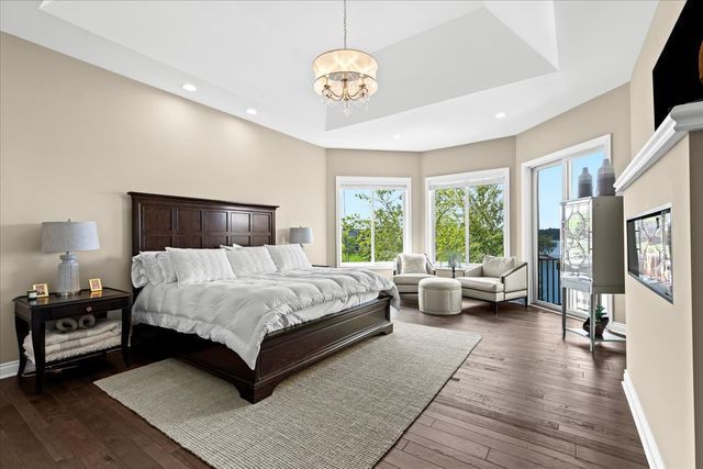 bedroom with dark hardwood / wood-style flooring, a notable chandelier, and a raised ceiling