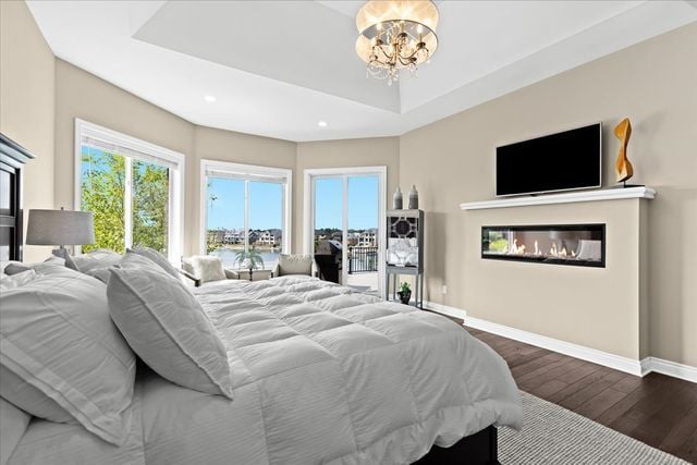 bedroom with a raised ceiling, dark wood-type flooring, and a notable chandelier