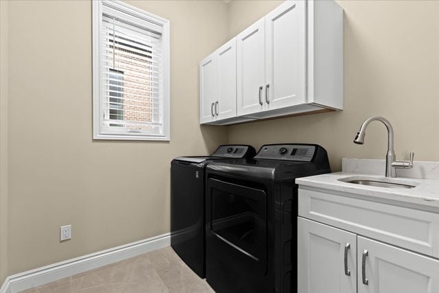 washroom with light tile patterned flooring, cabinets, sink, and washing machine and dryer