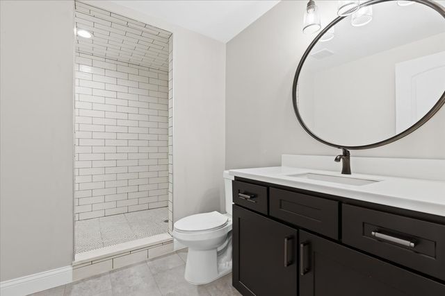 bathroom with tiled shower, vanity, and toilet