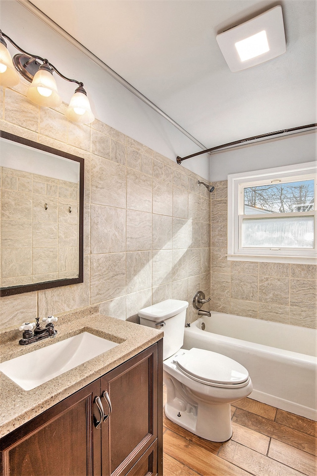 full bathroom with vanity, toilet, tiled shower / bath combo, and tile walls