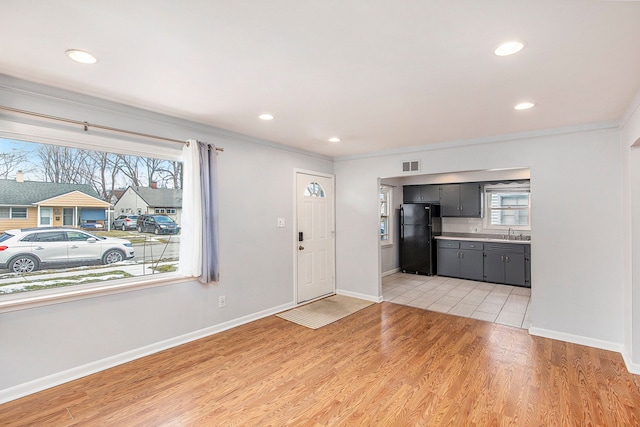 foyer entrance with ornamental molding, sink, and light hardwood / wood-style flooring