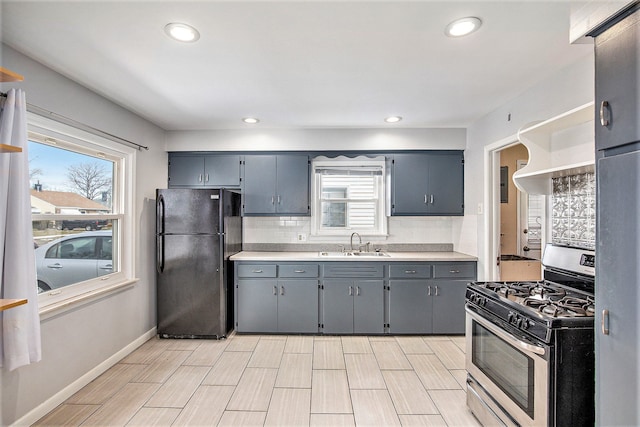 kitchen with gray cabinets, sink, decorative backsplash, black fridge, and stainless steel gas range