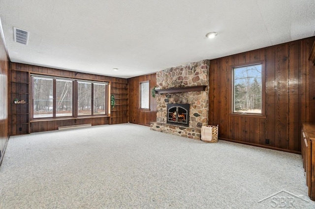 unfurnished living room featuring carpet flooring, a fireplace, and wood walls