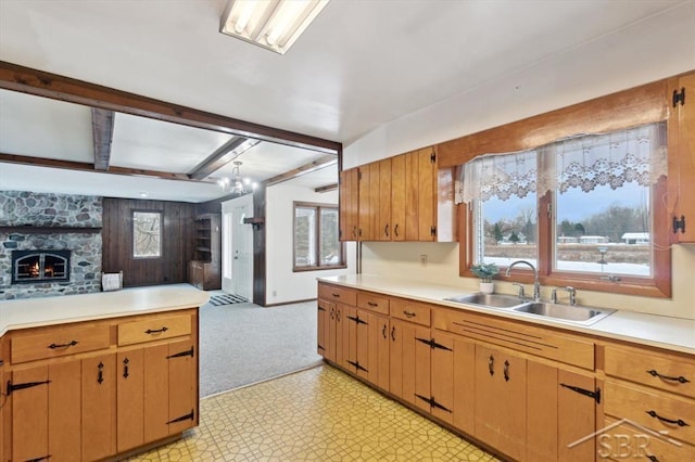 kitchen with beamed ceiling, a stone fireplace, and sink