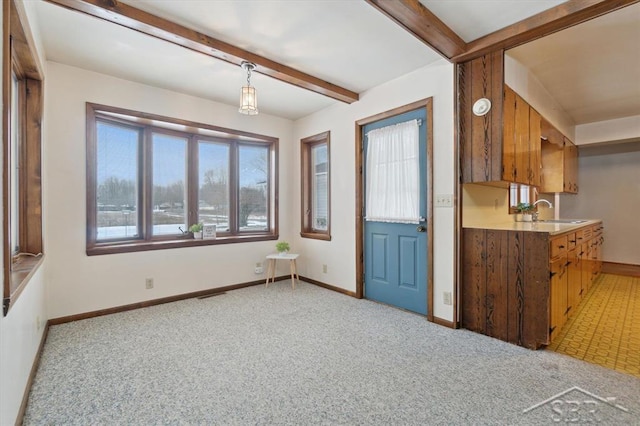 interior space with sink, light carpet, beam ceiling, and decorative light fixtures