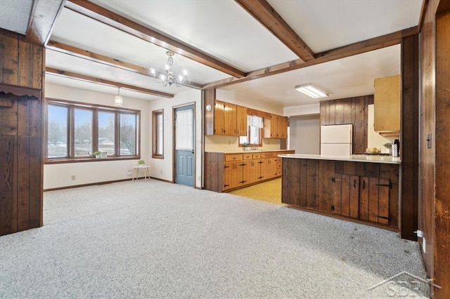 kitchen featuring decorative light fixtures, beam ceiling, white fridge, light carpet, and an inviting chandelier