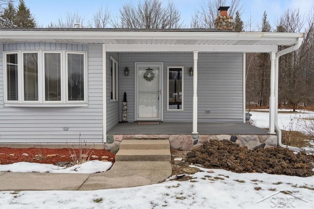 snow covered property entrance with a porch