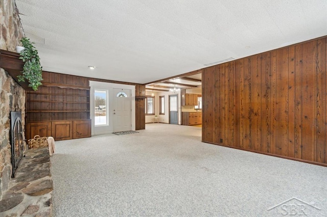 unfurnished living room with carpet flooring, a textured ceiling, and wood walls