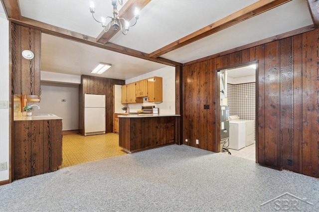 kitchen with sink, beam ceiling, wooden walls, separate washer and dryer, and white fridge