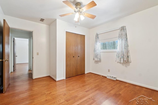 unfurnished bedroom featuring ceiling fan, a closet, and light wood-type flooring