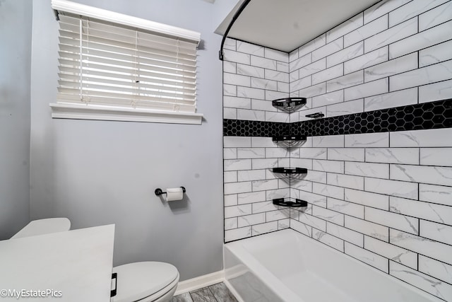 bathroom featuring tiled shower / bath combo and toilet