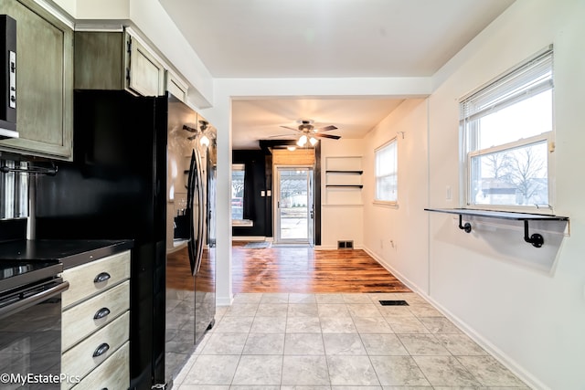 kitchen featuring a healthy amount of sunlight, light tile patterned floors, electric range, and green cabinetry