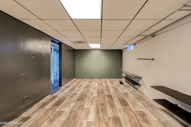 basement featuring a drop ceiling and light hardwood / wood-style flooring