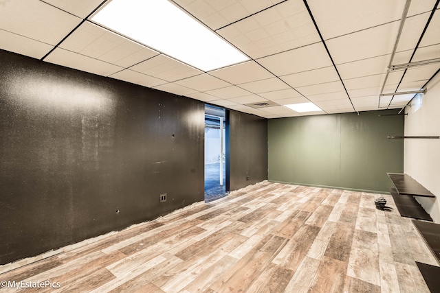 basement featuring a paneled ceiling and light hardwood / wood-style flooring