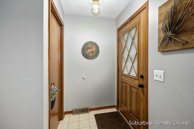 doorway to outside featuring light tile patterned floors and a textured ceiling