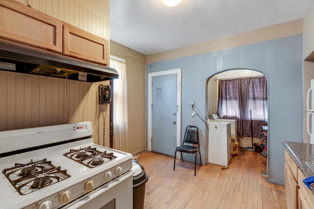 kitchen with light brown cabinetry, white gas range, and light hardwood / wood-style flooring