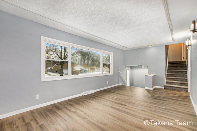 unfurnished living room featuring hardwood / wood-style floors and a textured ceiling