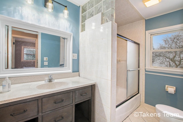 full bathroom featuring combined bath / shower with glass door, tile patterned flooring, vanity, ornamental molding, and toilet