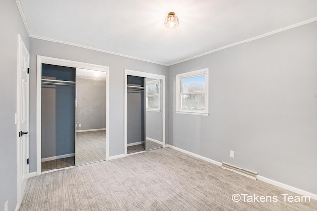 unfurnished bedroom with crown molding, carpet floors, and multiple closets