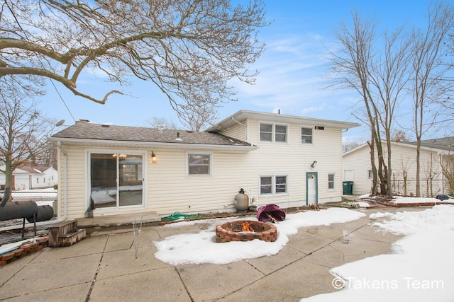 snow covered back of property featuring a patio and a fire pit