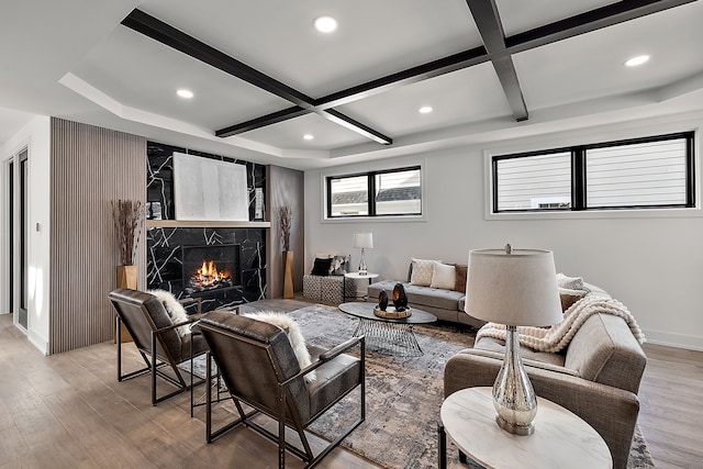 living room with beamed ceiling, a high end fireplace, coffered ceiling, and light wood-type flooring