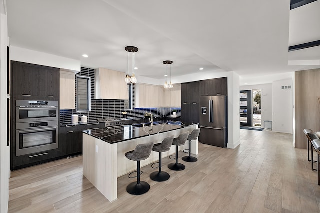 kitchen featuring sink, a kitchen breakfast bar, hanging light fixtures, a kitchen island with sink, and stainless steel appliances