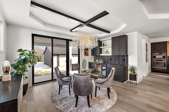 dining area featuring coffered ceiling, a notable chandelier, and light hardwood / wood-style flooring