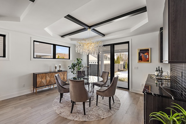 dining area with beamed ceiling, a chandelier, and light hardwood / wood-style flooring