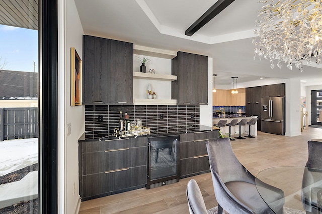 kitchen with wine cooler, dark brown cabinetry, high end refrigerator, and decorative backsplash