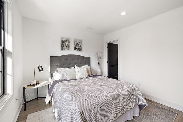 bedroom with multiple windows and light hardwood / wood-style flooring