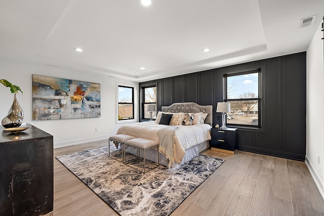 bedroom featuring light hardwood / wood-style floors and a tray ceiling