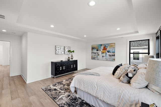 bedroom featuring a tray ceiling and light hardwood / wood-style floors