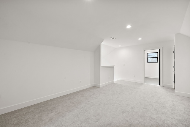 spare room featuring vaulted ceiling and light colored carpet